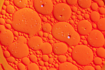 Drops of oil on the surface of the water. Abstract colored background.
