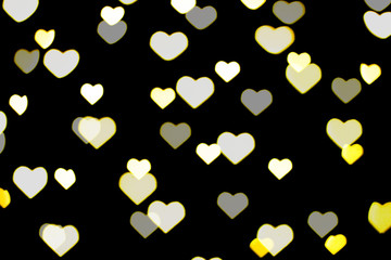 Beautiful yellow and white bokeh on a black background. Can be used as a background or wallpaper. Heart shape. Love Concept, Valentine's Day