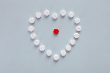 medicine, healthcare and pharmacy concept - pills and of drugs in shape of the heart and heart rhythms.