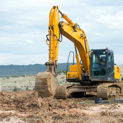 Fototapeta na wymiar Yellow excavator at construction site into mud with sky background