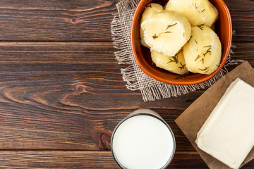 Fototapeta premium Boiled potato in brown bowl, milk and butter on dark wooden background.