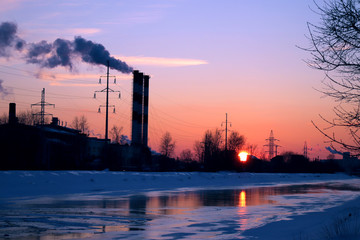 Sunset in the winter city, environmental pollution, frozen river.