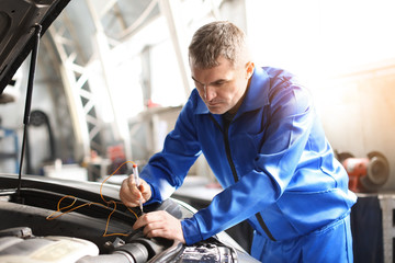 Male mechanic examining car in service center