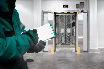 Hand of worker with clipboard checking goods in freezing room or warehouse. Export-Import Logistics...