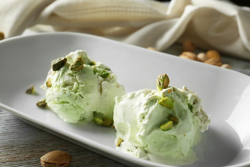 Plate with tasty pistachio ice-cream on wooden table