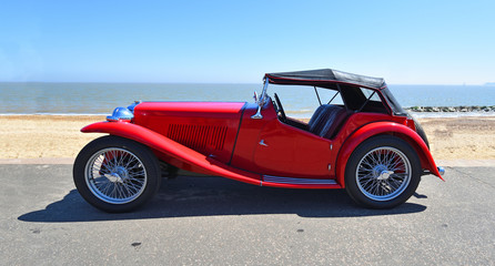 Classic Red Sports Car parked on Seafront  Promenade. - obrazy, fototapety, plakaty
