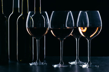 Bottles of wine and different glasses of wine on a dark background
