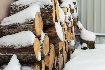 Chopped stock of firewood under snow on the street. Firewood for fireplace and bbq
