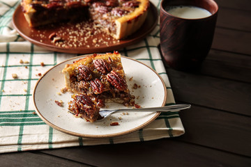 Tasty pecan pie with milk on wooden table