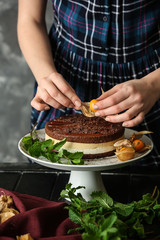 Female confectioner decorating tasty cake at table