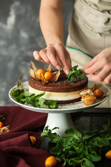 Female confectioner decorating tasty cake at table