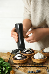 Female confectioner decorating tasty tartlets at table