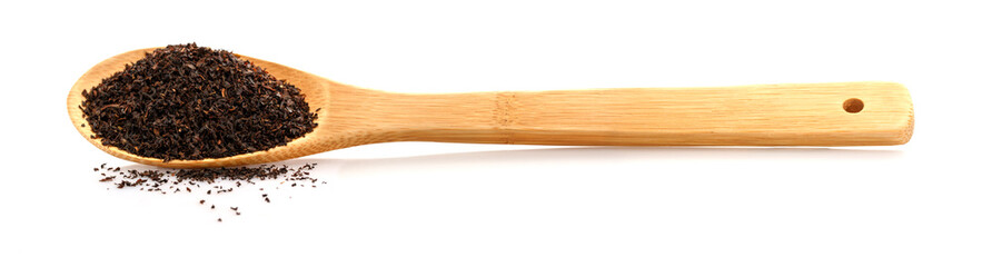 Black tea in a wooden spoon. Large leaf tea. Isolated on white background.