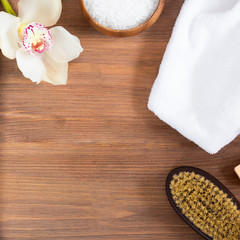 woman body and skincare, massage and bath products, sea salt in bowl, white towel, flower, cacus brush for dry massage on brown wooden background. Beauty blogger cosmetics Copy space Mockup Square