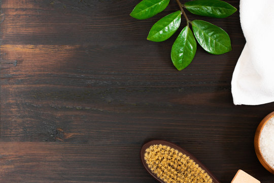 woman body and skincare, massage and bath products, sea salt in bowl, white towel, green leaves, cacus brush for dry massage on black wooden background. Beauty blogger cosmetics Copy space Horizontal