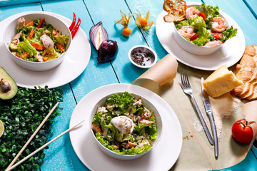 Greek salad background. Bowl with fresh greek salad, tomatoes, olives, olive oil on wooden table. Space for text. Top view. Traditional greek dish. Ingredients for making salad. Mediterranean diet