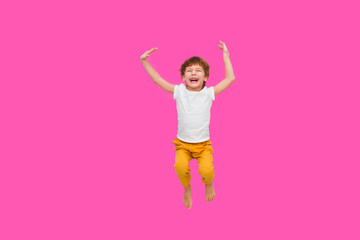 Cheerful little boy  jumping on a pink background