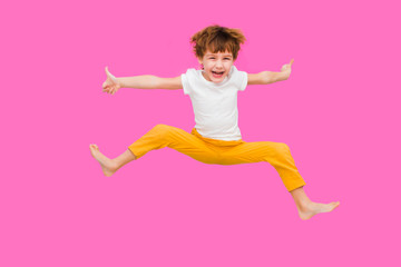 Cheerful little boy  jumping on a pink background