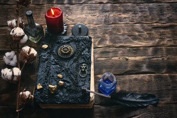 Branch of cotton tree and book of magic on a brown wooden table background with copy space.