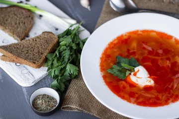 Traditional Ukrainian Russian borsch with sour cream and white beans on a dark background. Red vegetable beetroot soup.
