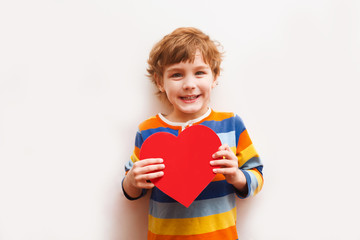 smiling little child six years old holds paper heart on white background. happy mother's day!
