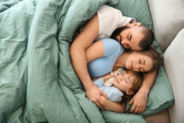 Happy family sleeping in bed at home - Powered by Adobe