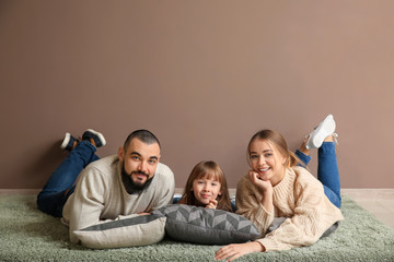 Happy family lying on carpet near color wall