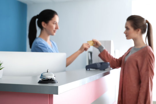 Female receptionist receiving payment for medical service from patient in clinic