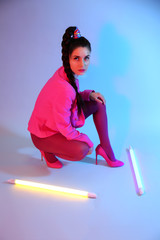 Toned portrait of beautiful young woman with neon lamps on color background
