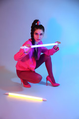 Toned portrait of beautiful young woman with neon lamps on color background