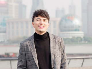 Portrait of a handsome Chinese young man in casual suit smiling and looking at camera confidently...