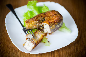 piece of fried pike fish in a plate on a wooden