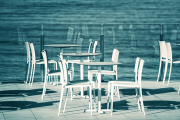 White tables and chairs in empty cafe by the sea