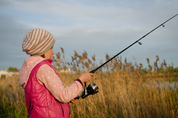a girl in a pink vest, spring, in sunny weather, fishing for spinning