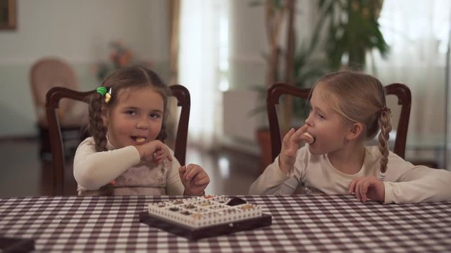 Two cute small sisters tastes chocolate tasty sugar-free candy ball after dinner and thy like it very much. Slow motion