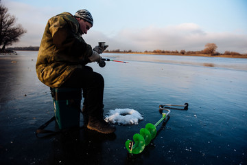 A man is fishing on the ice in the winter. Winter fishing