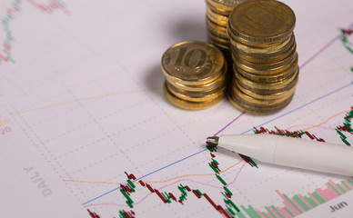 Pen on a colourful diagram. Coins in the background.