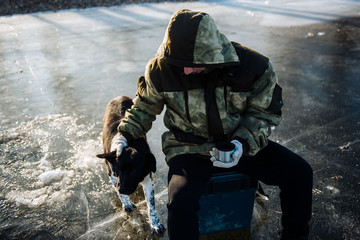 Fisherman drinking tea from a thermos in the winter on the ice. Winter fishing