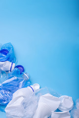 Used unsorted clean garbage in a pile. Bottles, bags and paper on blue background. Waste sorting. Place for text