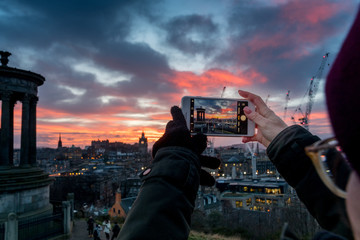 Fototapeta na wymiar smartphone photographer over the City of Edinburgh at sunset