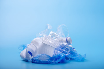 Used unsorted garbage in a pile. Bottles, bags and paper on blue background. Waste sorting. Place for text