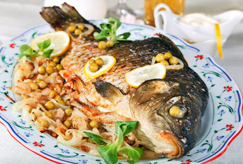 Baked carp served with fried onion and vegetables.