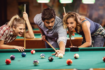 Obraz na płótnie Canvas friends shooting pool ball playing snooker together.