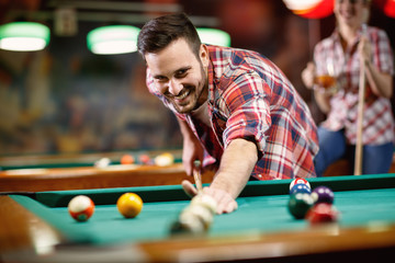Young smiling man playing billiard . - obrazy, fototapety, plakaty