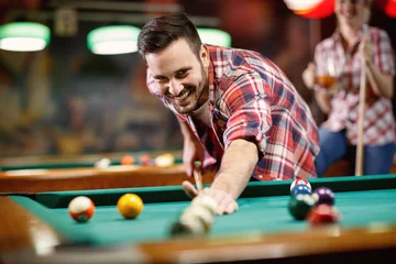 Foto op Plexiglas Young smiling man playing billiard . © luckybusiness
