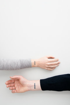 A Couple With Matching Minimal Tattoos Laying Out Their Arms Together.