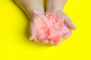 Woman holding exotic feathers colored in living coral.Concept of Easter celebration