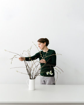 Young Woman Tending To Flowers In White Vase