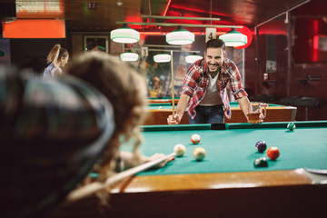 smiling man enjoying playing pool with friends.