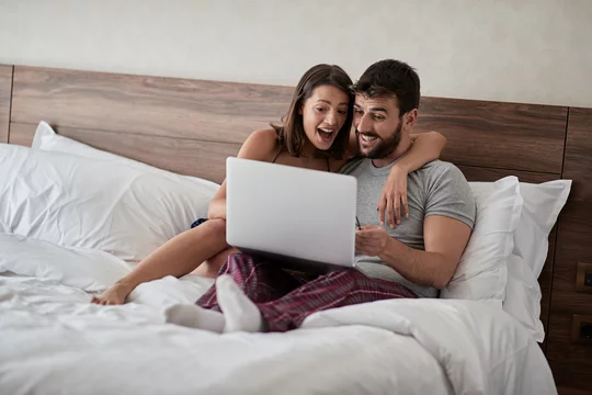 Romantic Bed Sex - Happy couple lying on a bed with computer - Beautiful married couple  watching sex video on laptop laughing together - People, sexual, technology  concept. Stock Photo | Adobe Stock